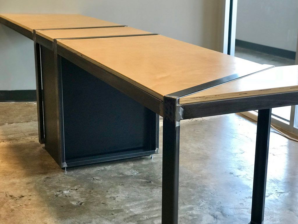 A wooden table with a metal frame is sitting on a concrete floor.