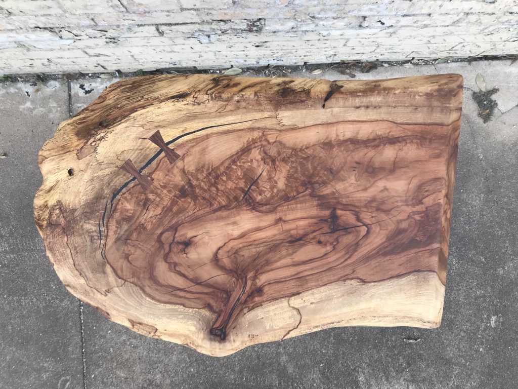 A piece of wood is sitting on the ground next to a brick wall.