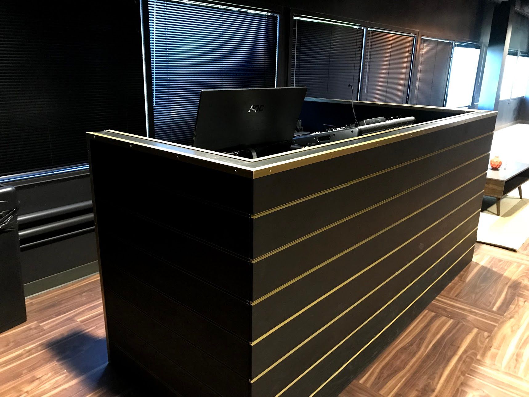 A black desk with a laptop on it in a room
