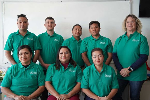 A group of people wearing green polo shirts are posing for a picture.