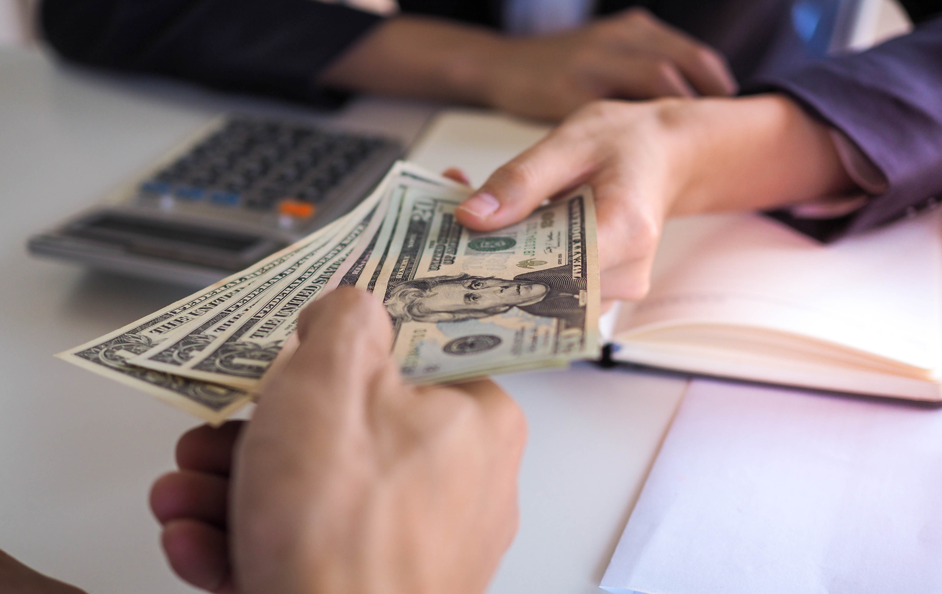 A person is handing another person a bunch of money.