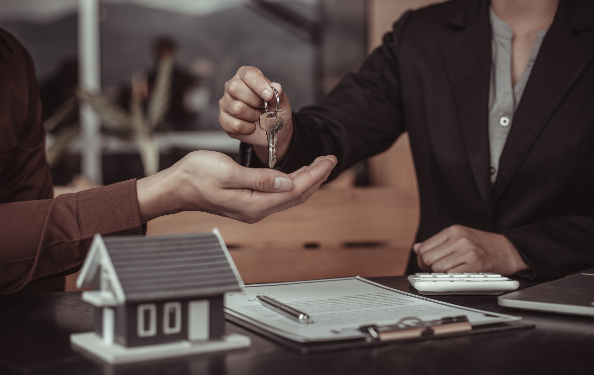 A woman is handing a set of keys to another woman.