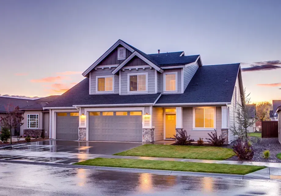 A large house with a garage and a driveway on a rainy day.