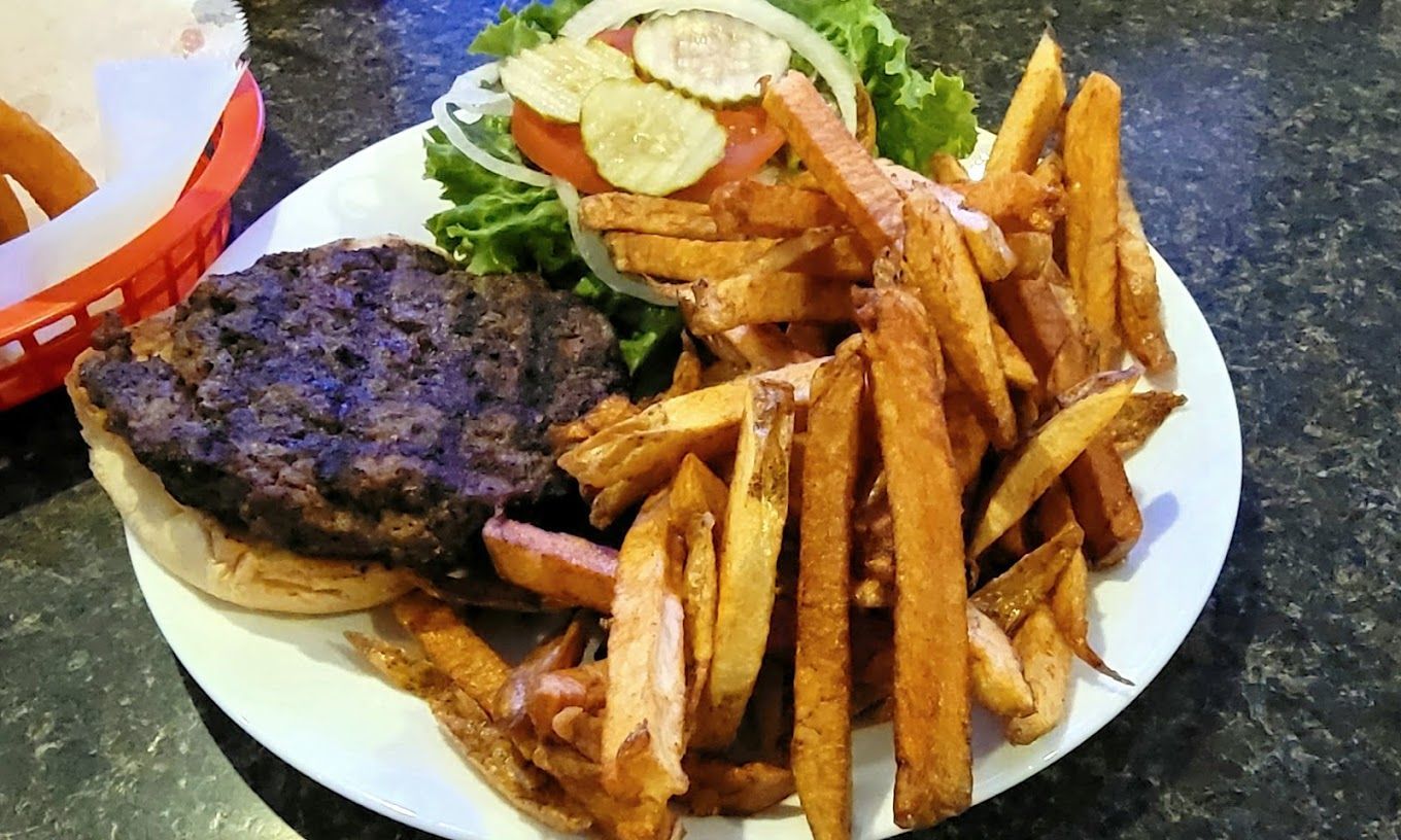 A plate of food with a hamburger and french fries on a table.