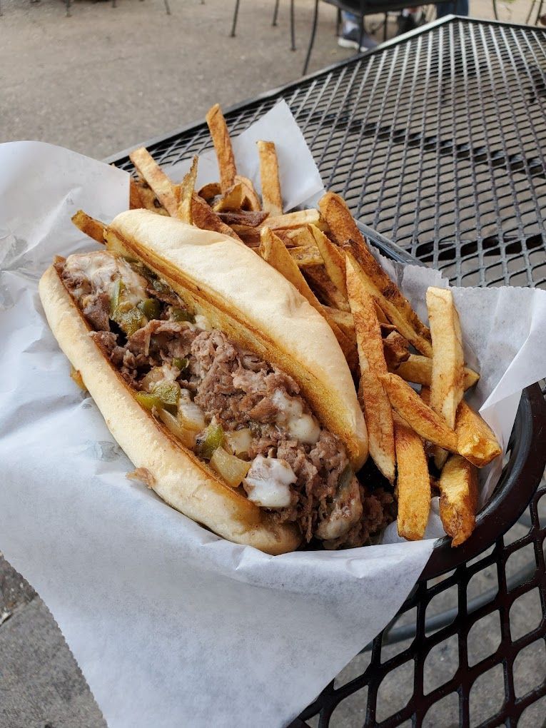 A sandwich and french fries in a basket on a table.