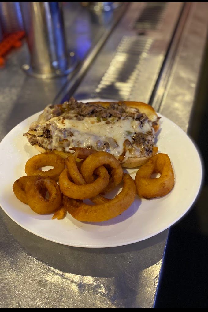 A plate of food with a sandwich and onion rings on a table.
