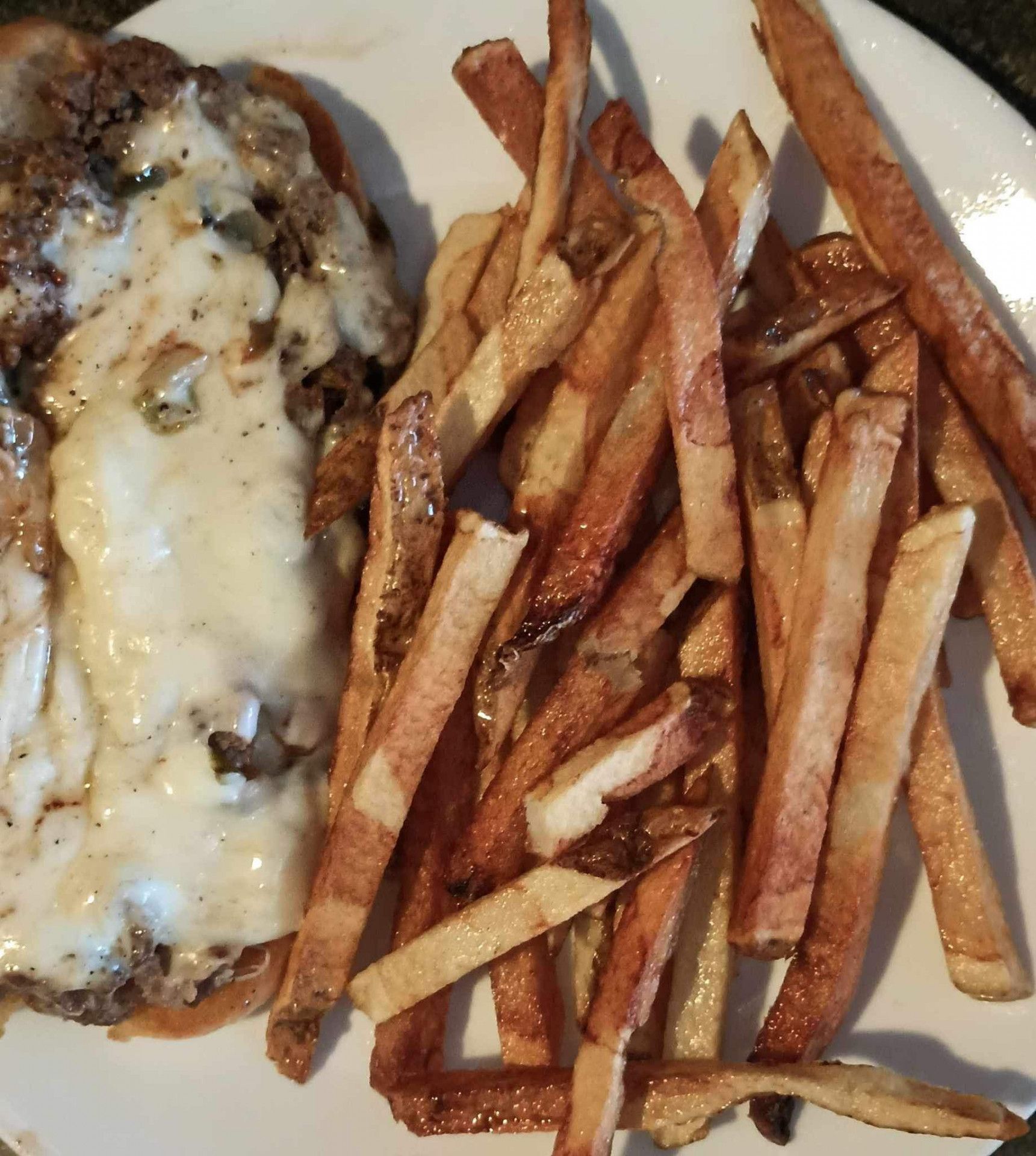 A white plate topped with french fries and a sandwich