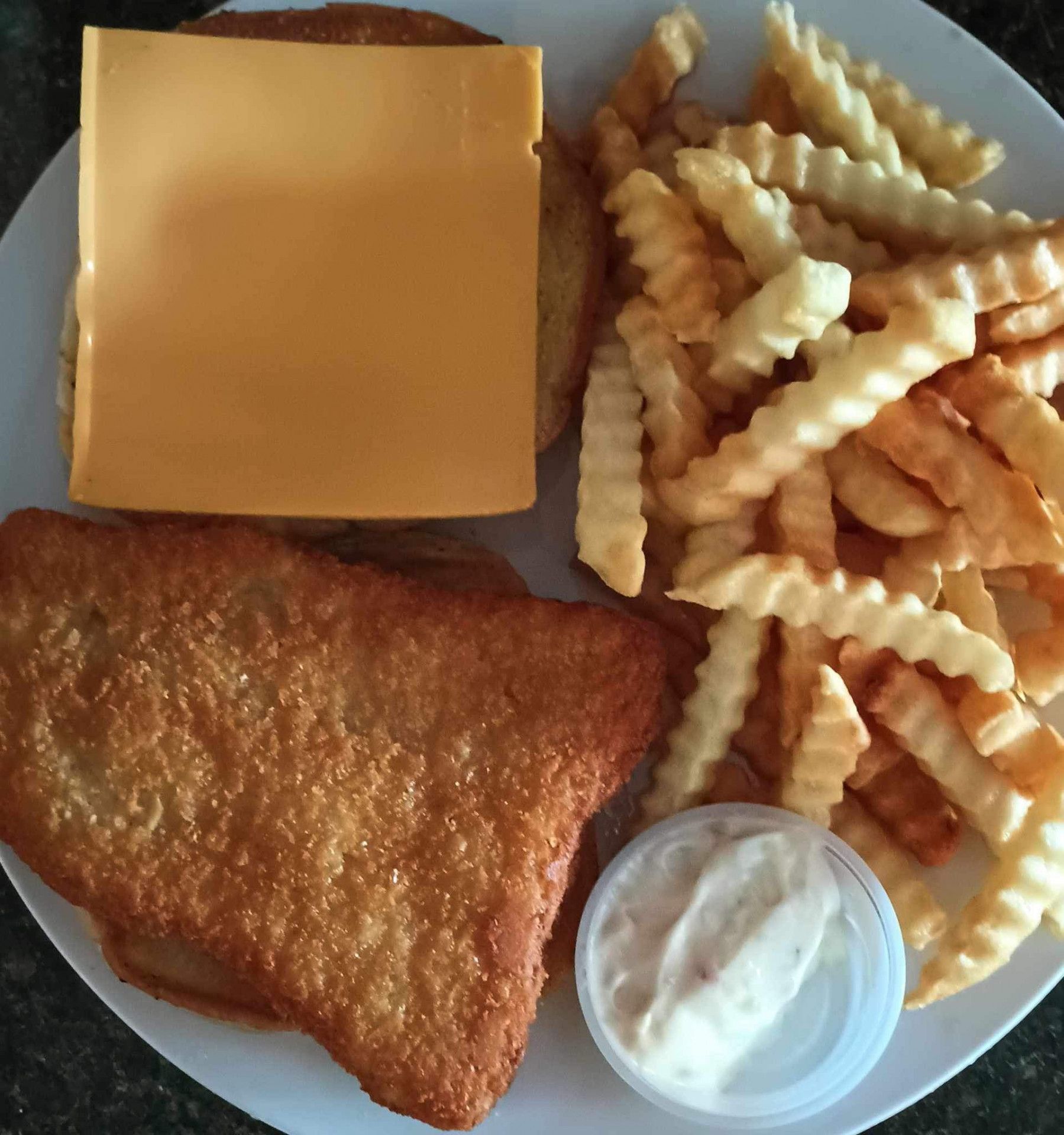 A white plate topped with french fries and a piece of cheese