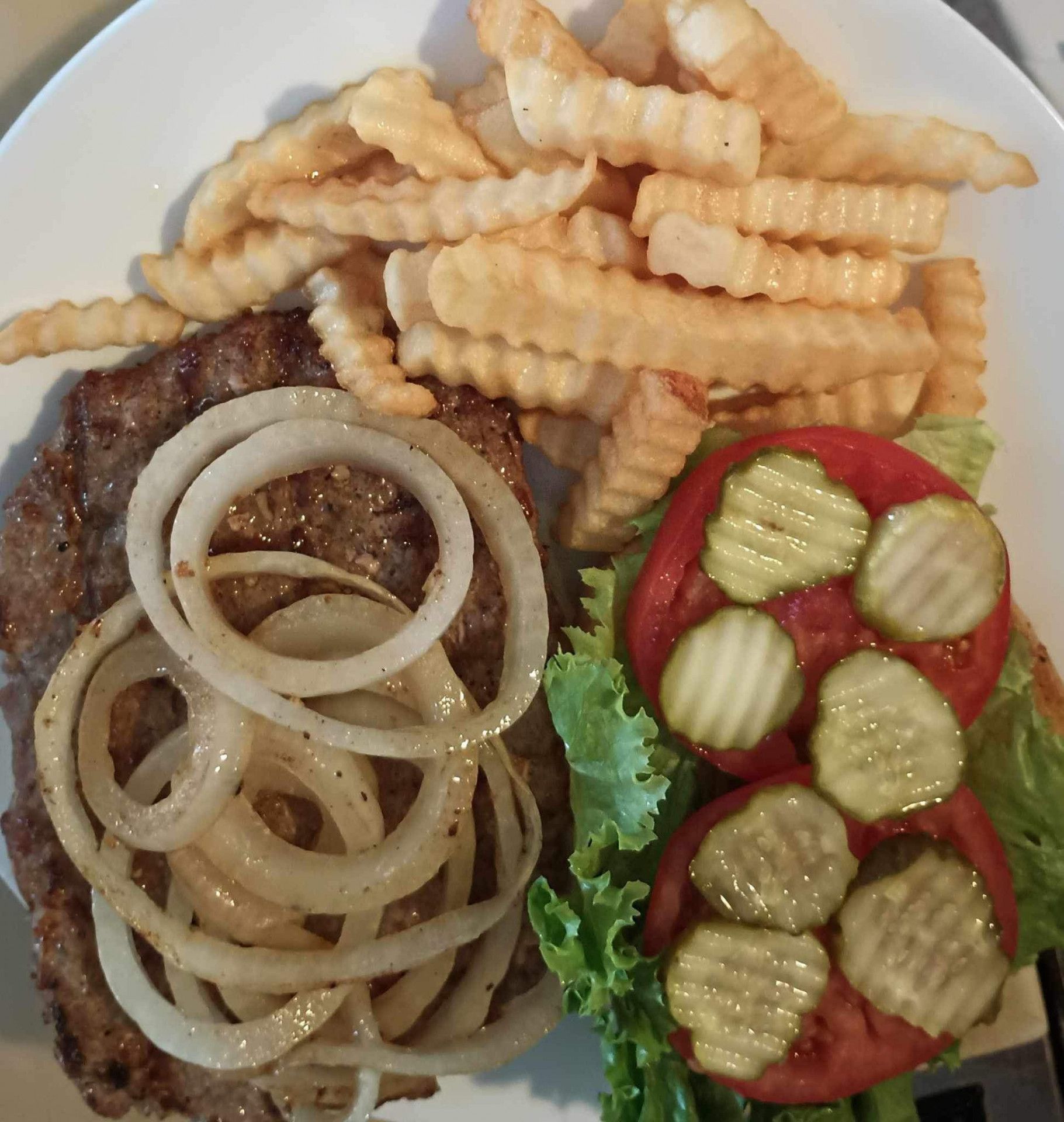 A white plate topped with a hamburger french fries and pickles