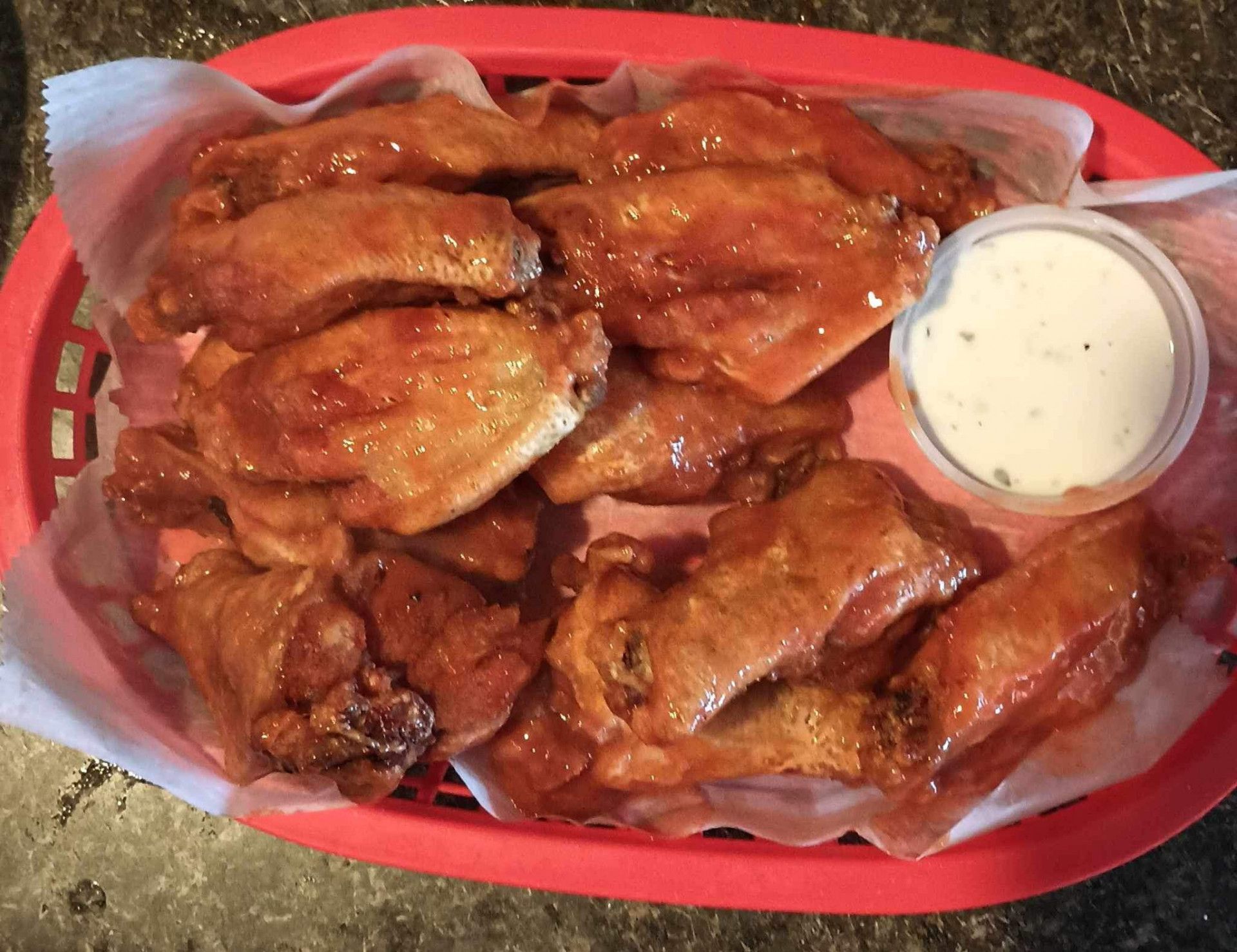A basket of chicken wings with a side of ranch dressing