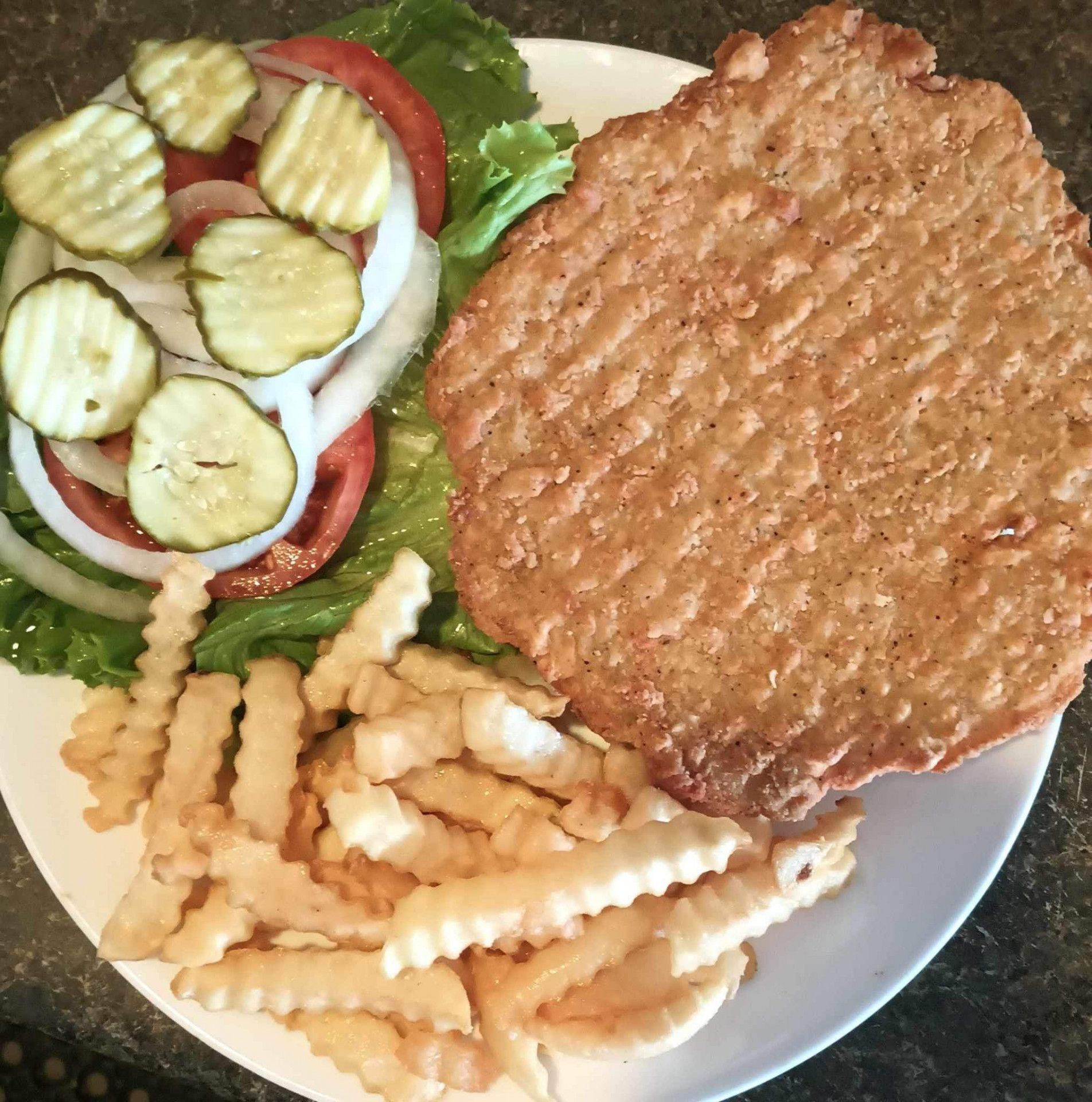 A white plate topped with french fries a hamburger and vegetables