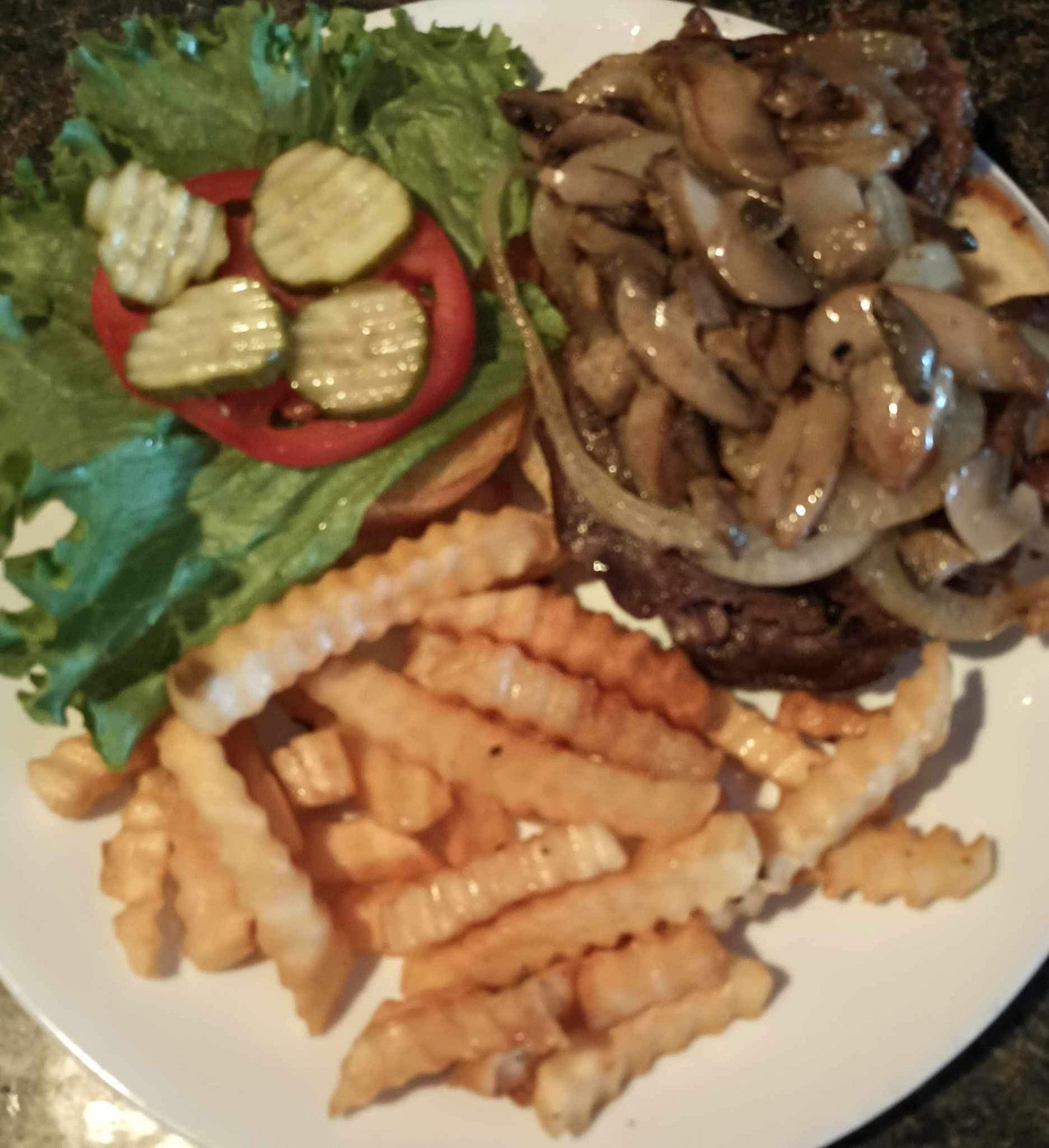 A white plate topped with french fries a hamburger and vegetables