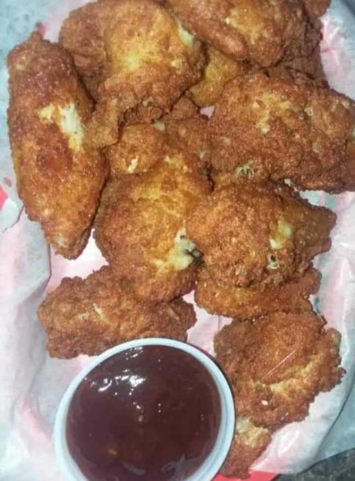 A basket of fried chicken wings with a dipping sauce