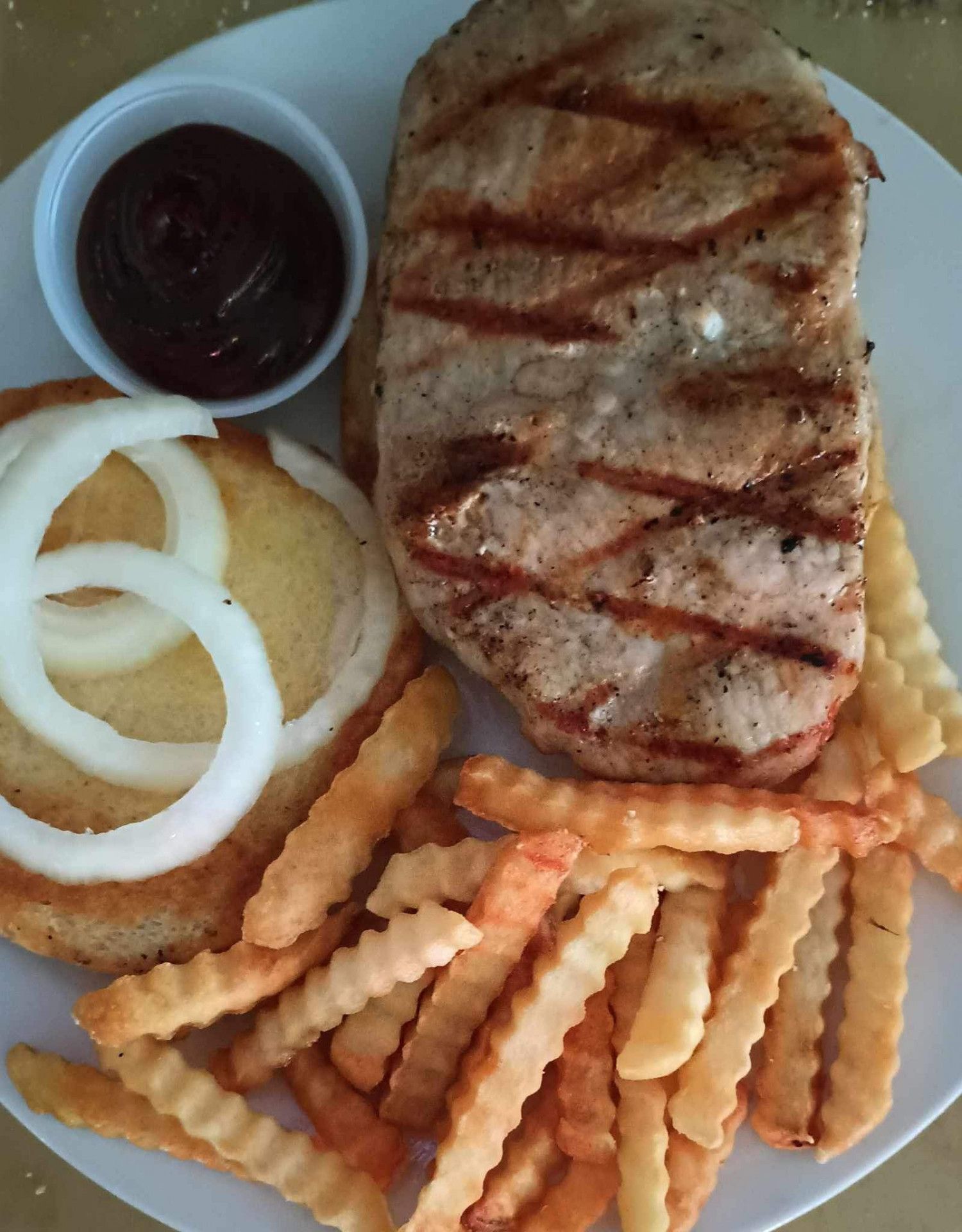 A white plate topped with french fries a hamburger and onions