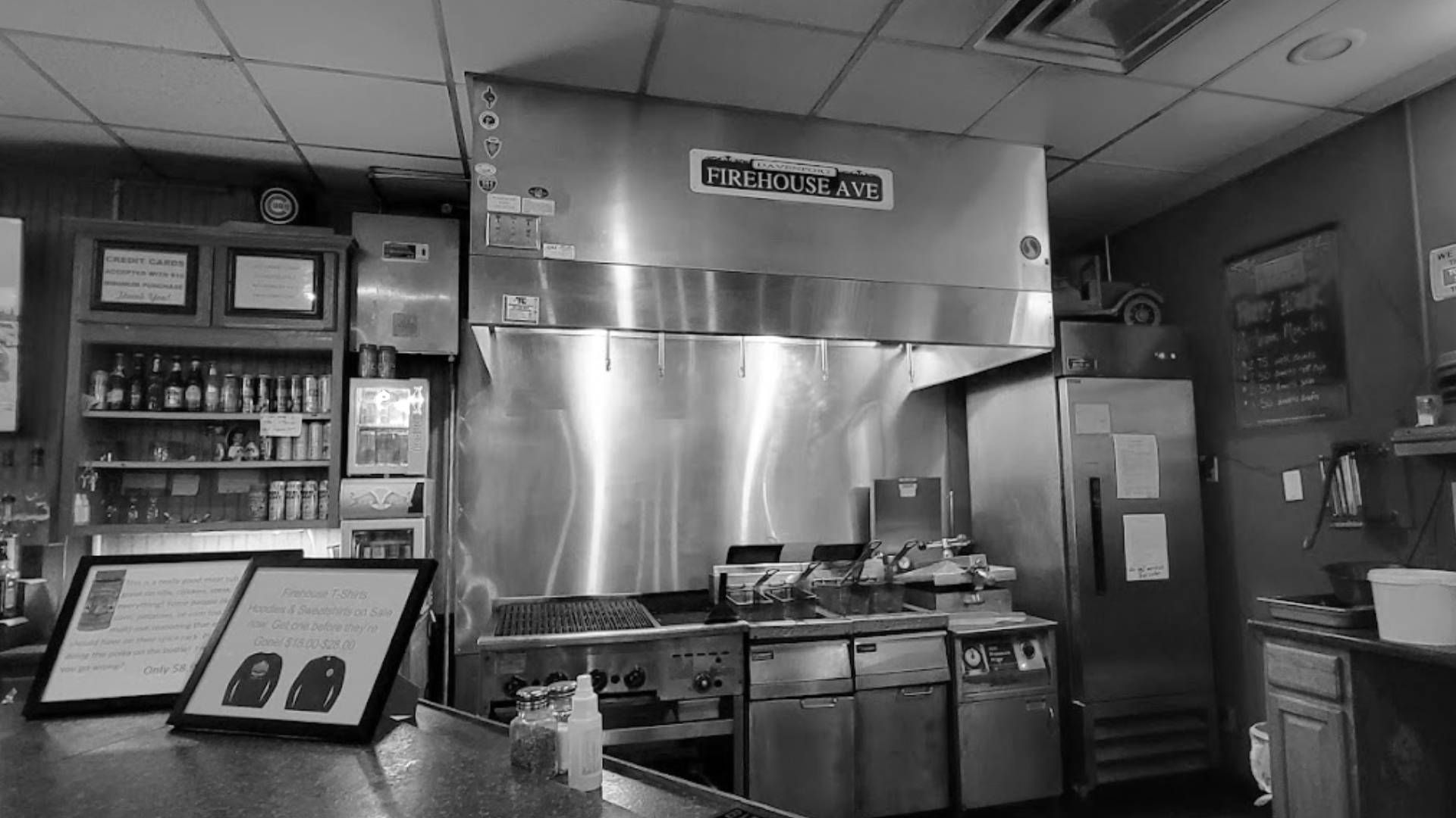 A black and white photo of a restaurant kitchen with stainless steel appliances