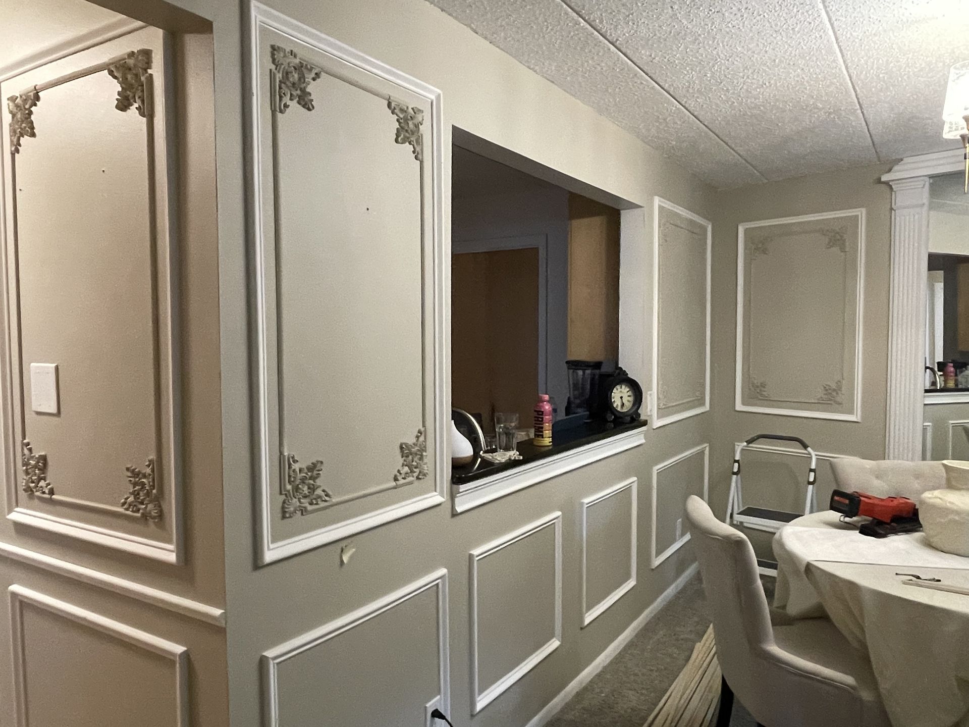 Dining room with beige walls, white trim, and rectangular wall panels.