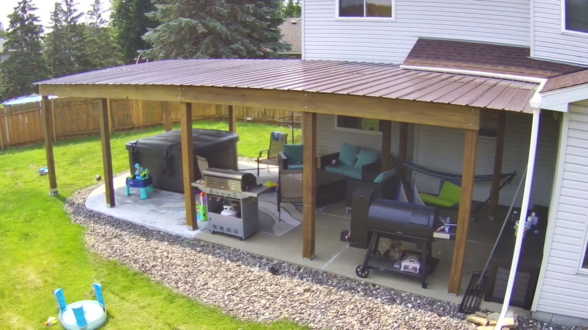 Backyard patio with a covered area, featuring a grill, hot tub, and seating.