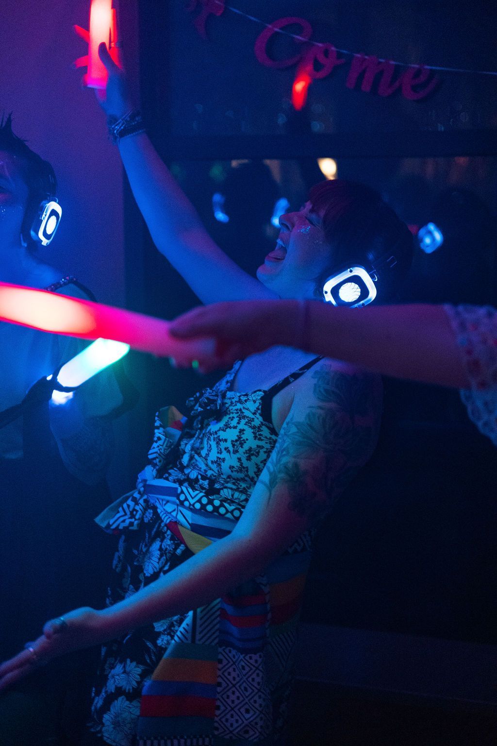 A woman wearing glow in the dark headphones is dancing at a party.