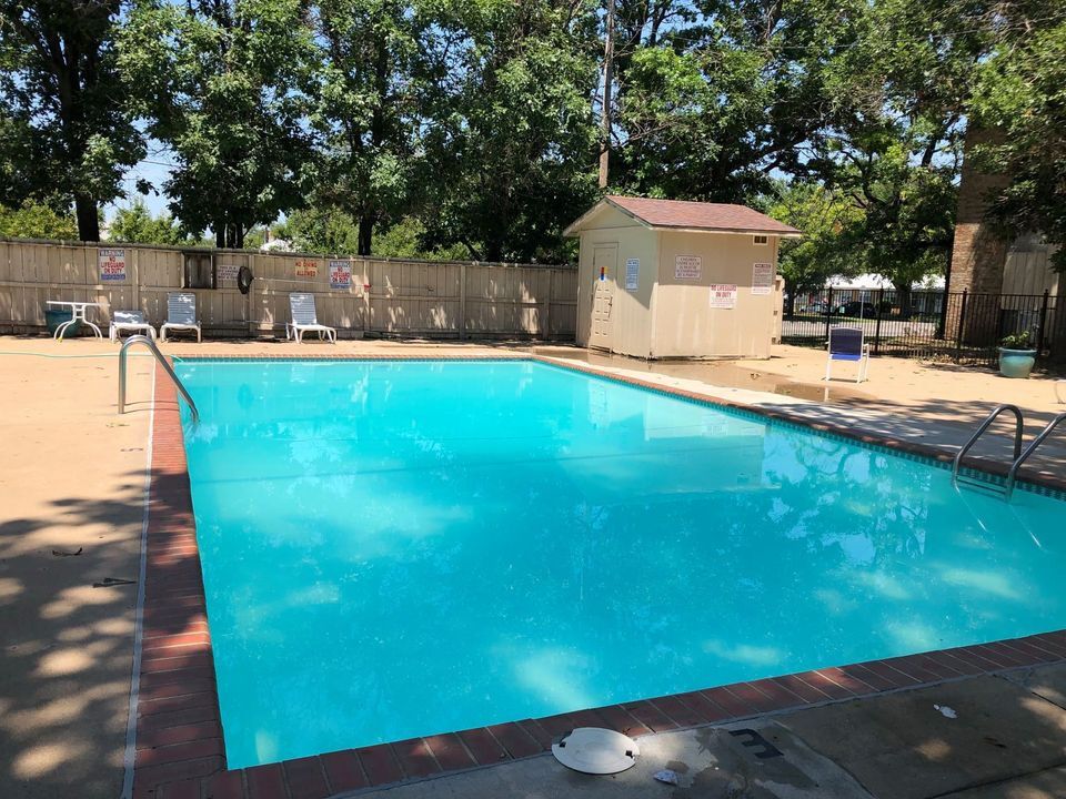 Swimming pool with turquoise water, lounge chairs, a small shed, and a wooden fence.
