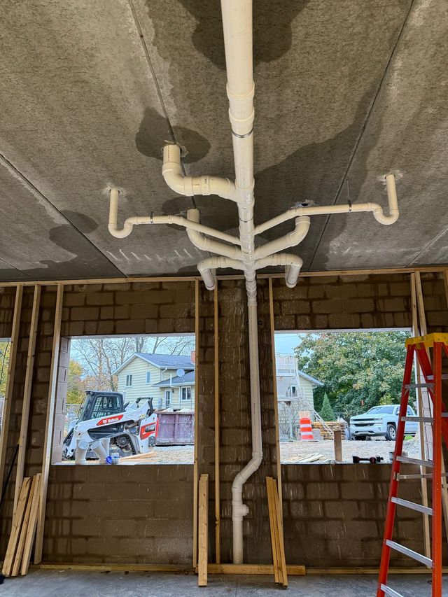 Unfinished room with exposed white HVAC piping on the ceiling and window openings showing a snowy street outside.