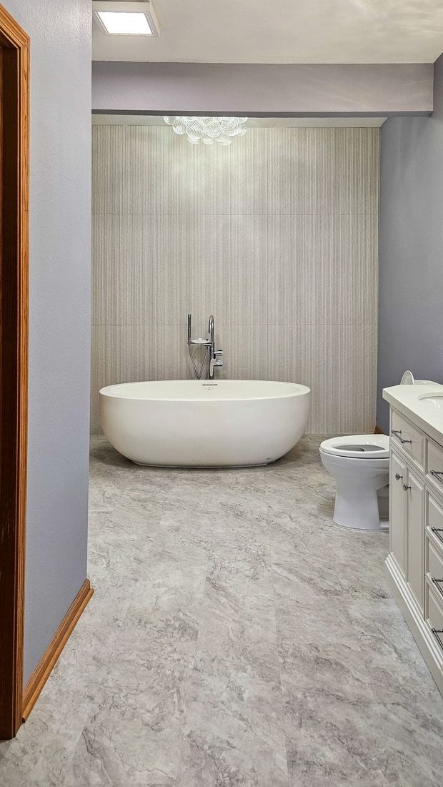 Modern bathroom with a freestanding tub, toilet, vanity, and light patterned tile floor