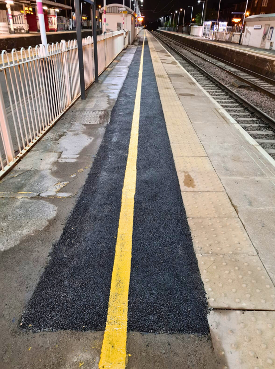 Empty train platform with a long black strip and yellow center line at night