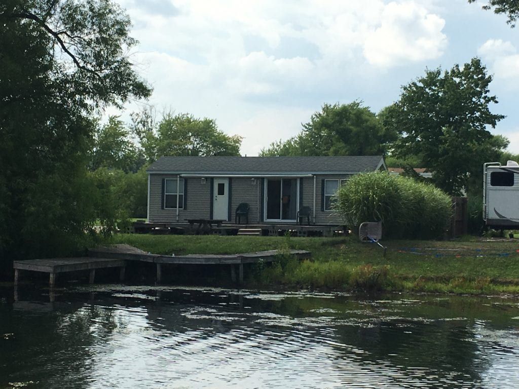 A small house sits on the shore of a lake