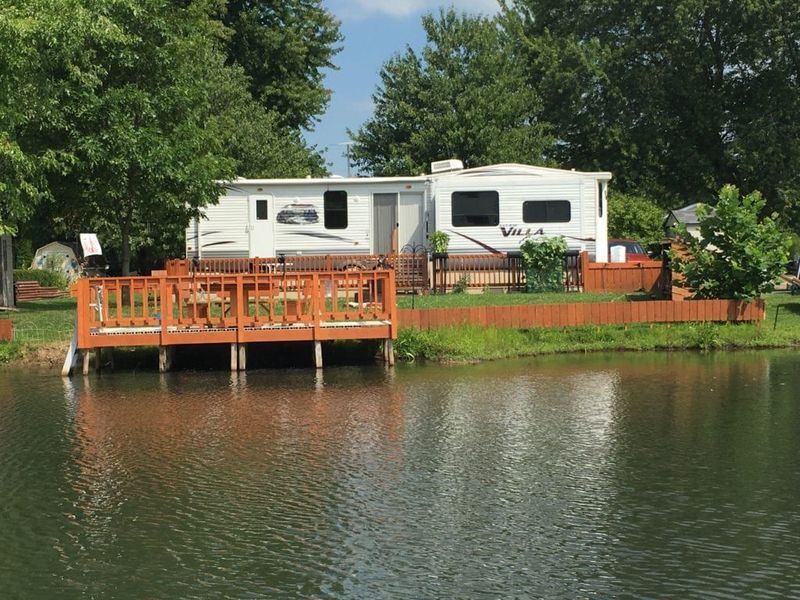 A rv parked on a dock next to a lake