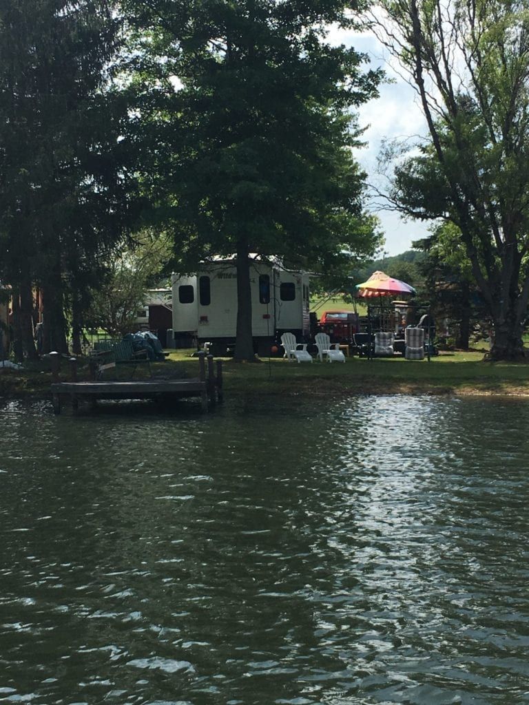 A rv is parked on the shore of a lake