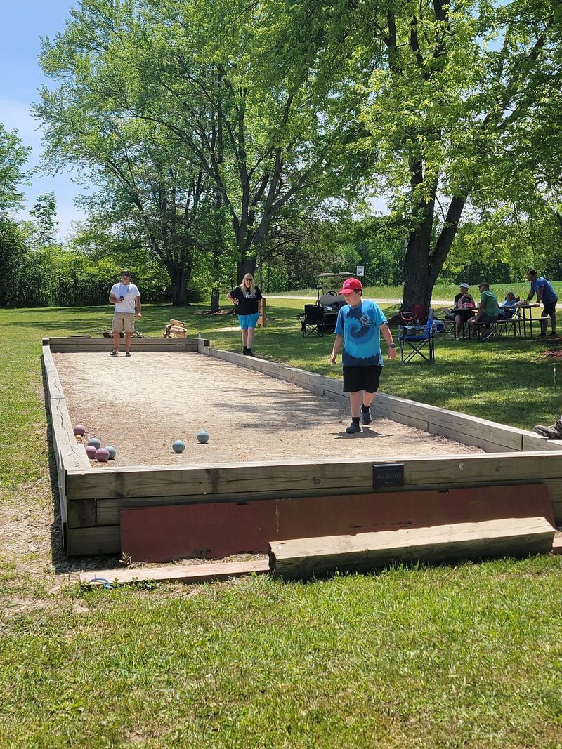 A group of people are playing bocce ball in a park