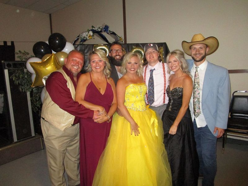 A group of people posing for a picture including a woman in a yellow dress