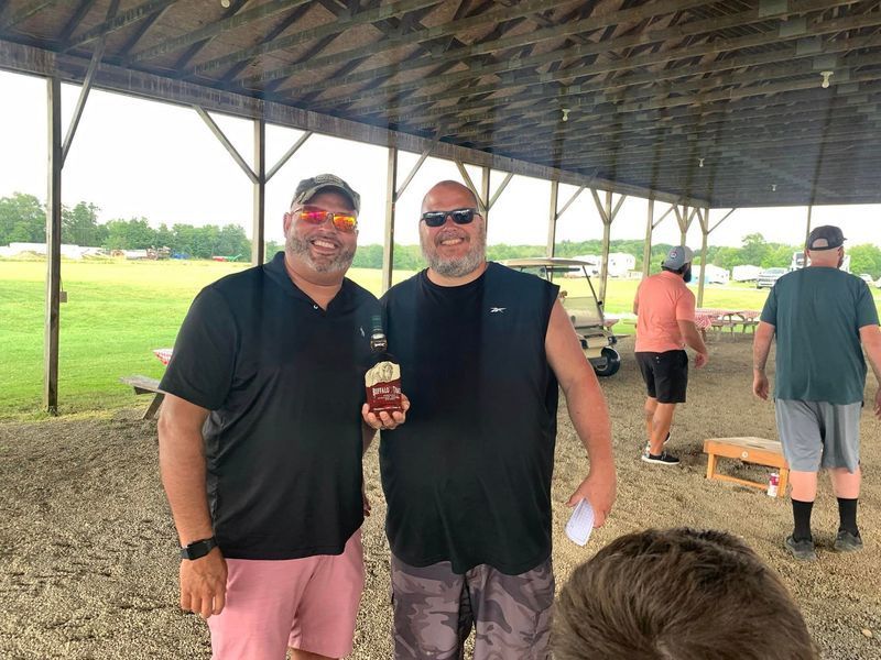 Two men are posing for a picture under a canopy