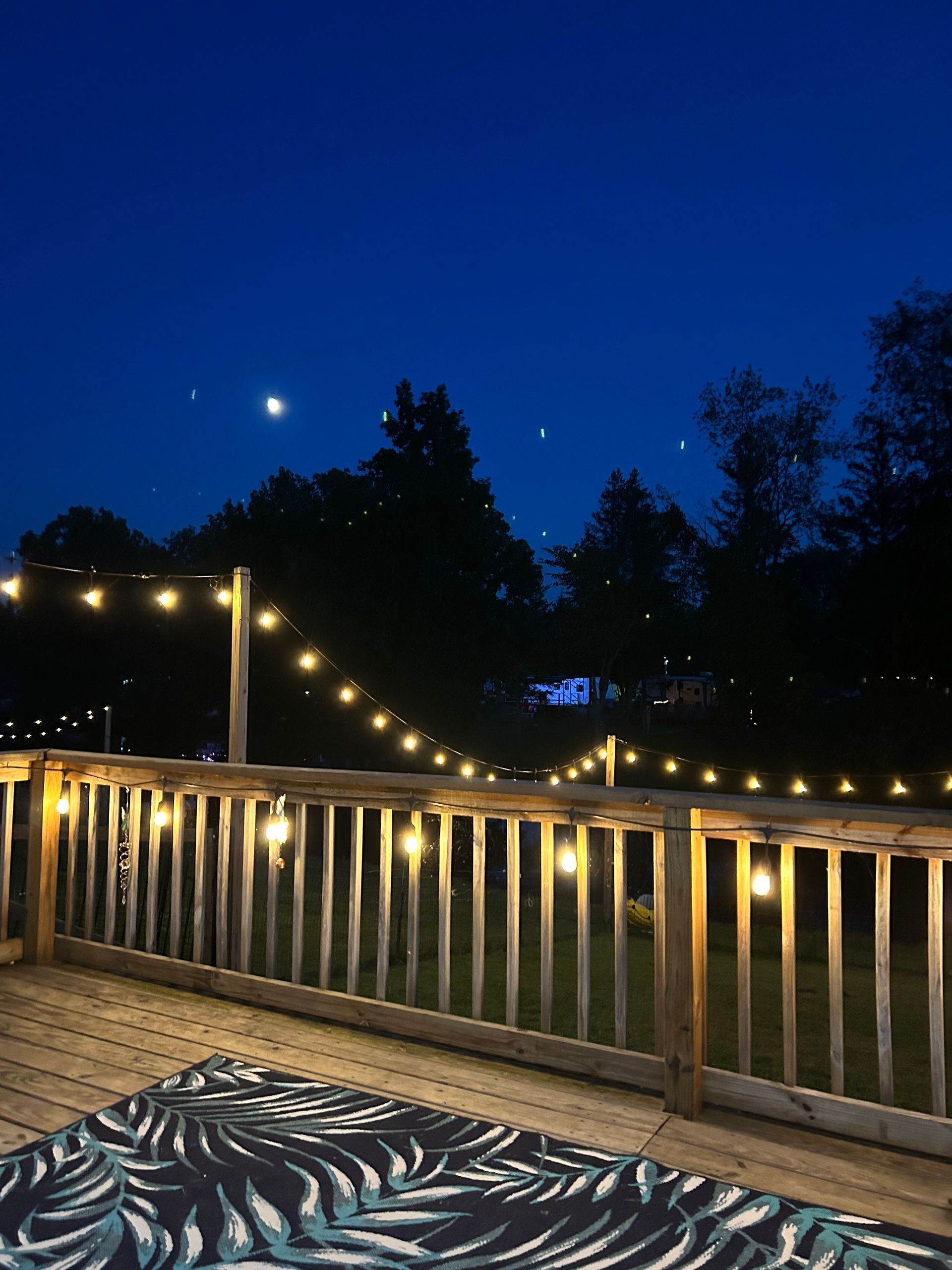 A deck with a rug and lights on it at night