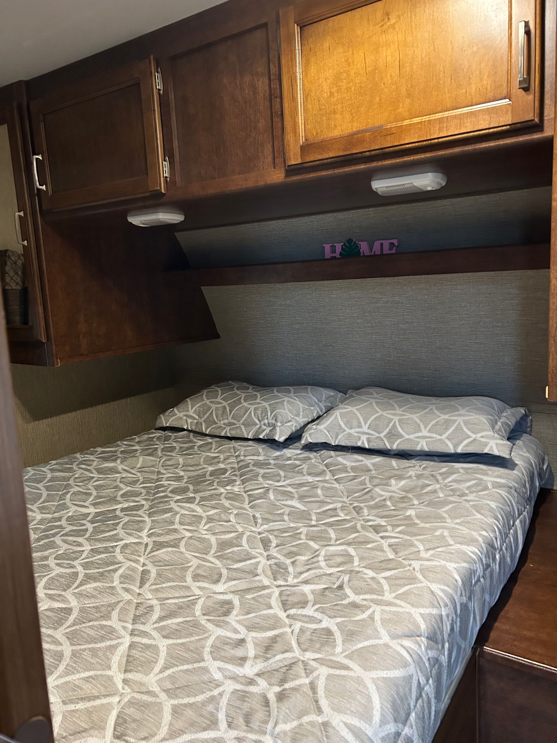 A bed with a mattress and pillows in a camper