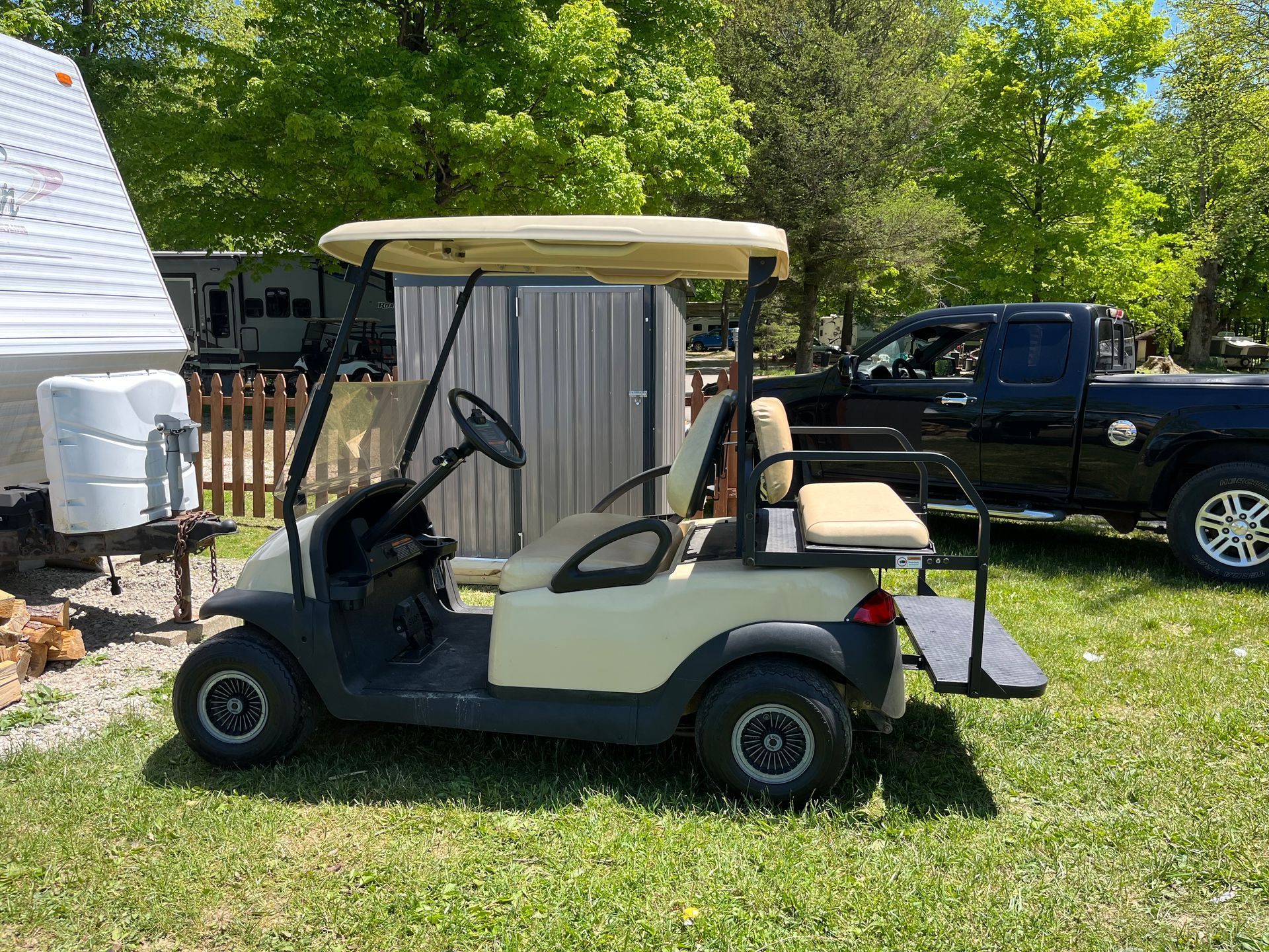 A golf cart is parked in the grass next to a truck