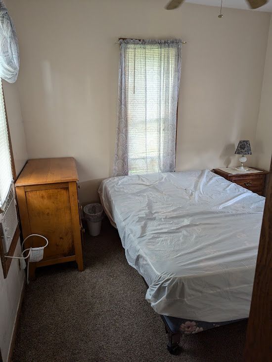 A bedroom with a bed, dresser, nightstand and window