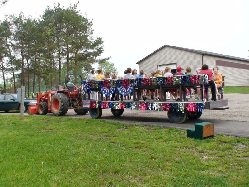 A tractor pulls a colorful wagon full of people
