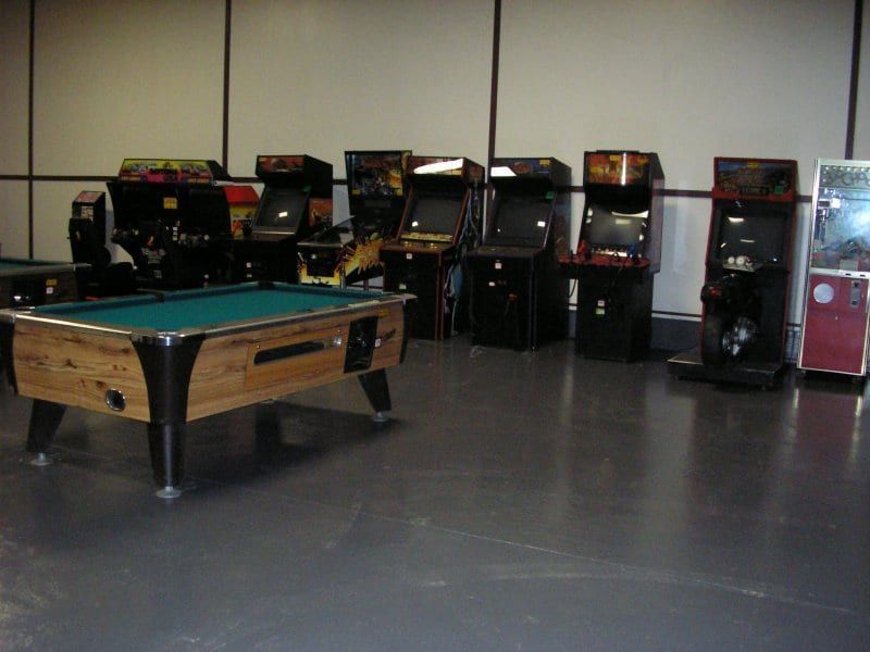 A pool table in a room filled with arcade games