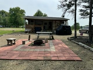 A house with a picnic table and a fire pit in front of it