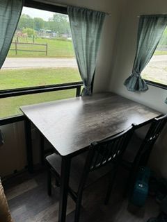 There is a table and chairs in the room with a window