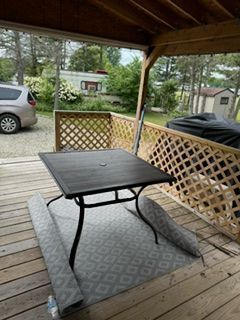 A table is sitting on top of a rug on a porch