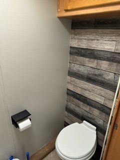 A bathroom with a toilet and a wooden wall