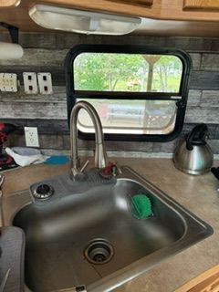 A stainless steel sink in a kitchen next to a window
