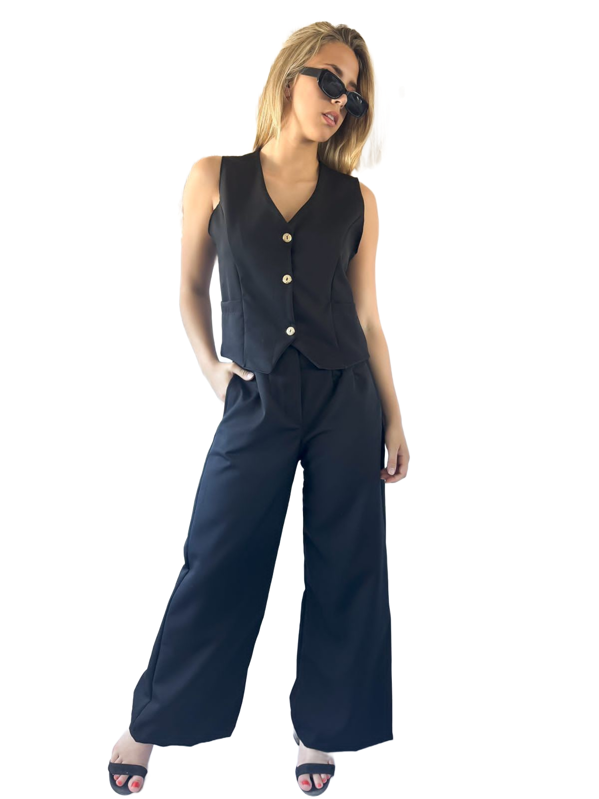 Mujer con chaleco negro y pantalones anchos con gafas de sol.