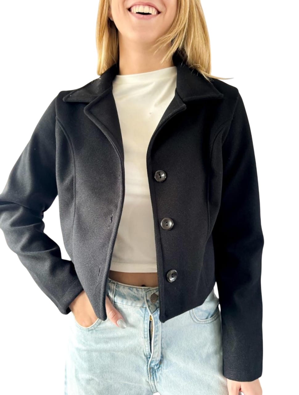 Mujer con blazer negro corto, top blanco y jeans.