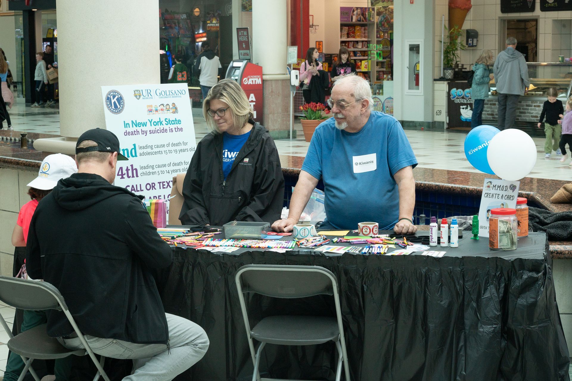 two presenters speaking with one guest at a table.