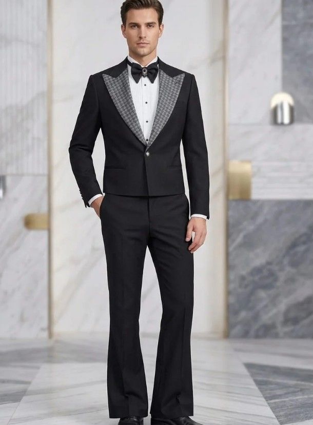Man in a black tuxedo adjusting his cufflinks, with warm blurred lights in the background