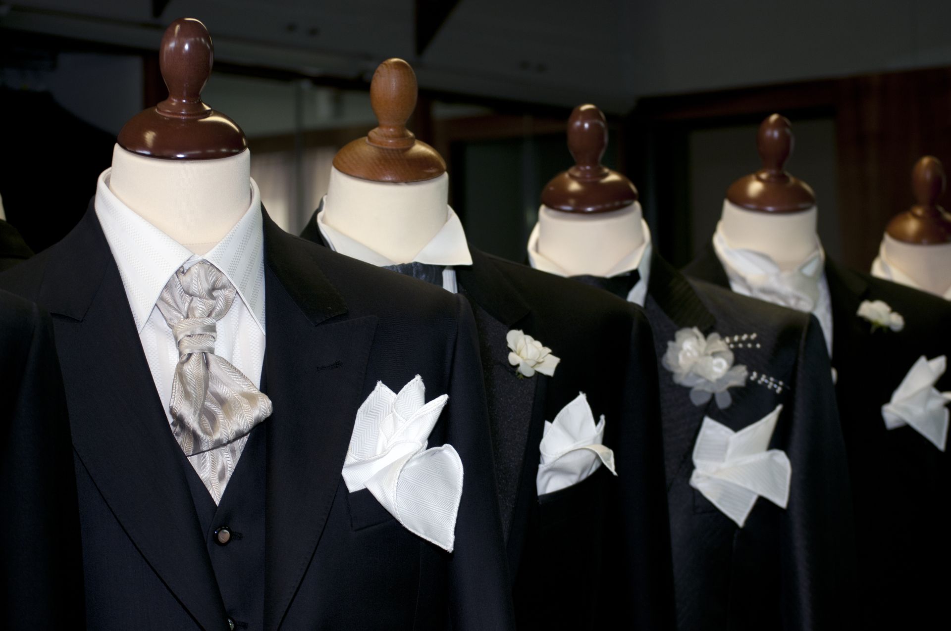 Mannequins dressed in black tuxedos with white pocket squares and neckties on display