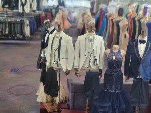 Mannequins in formal outfits displayed in a clothing store aisle
