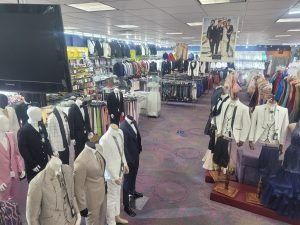 Clothing store interior with racks of suits and dresses under bright lights